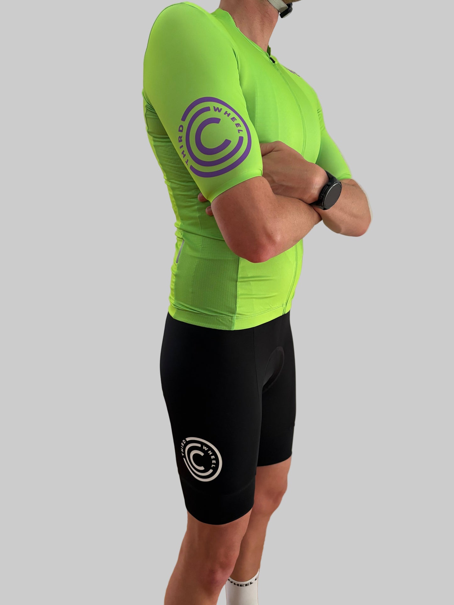 Person wearing a bright green cycling jersey and black shorts with a logo on a gray background