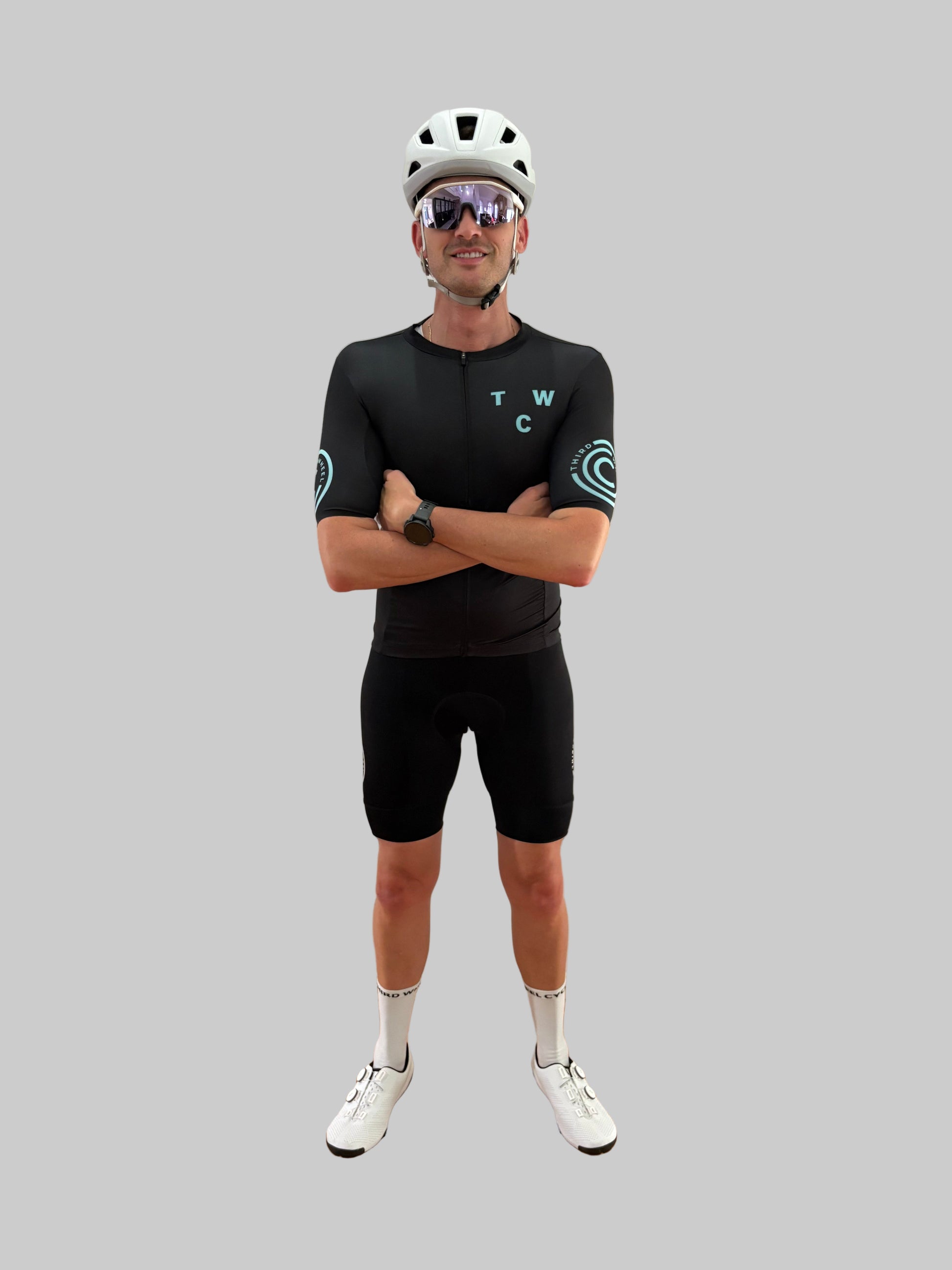 Person wearing a black cycling outfit with 'TWC' branding on a gray background