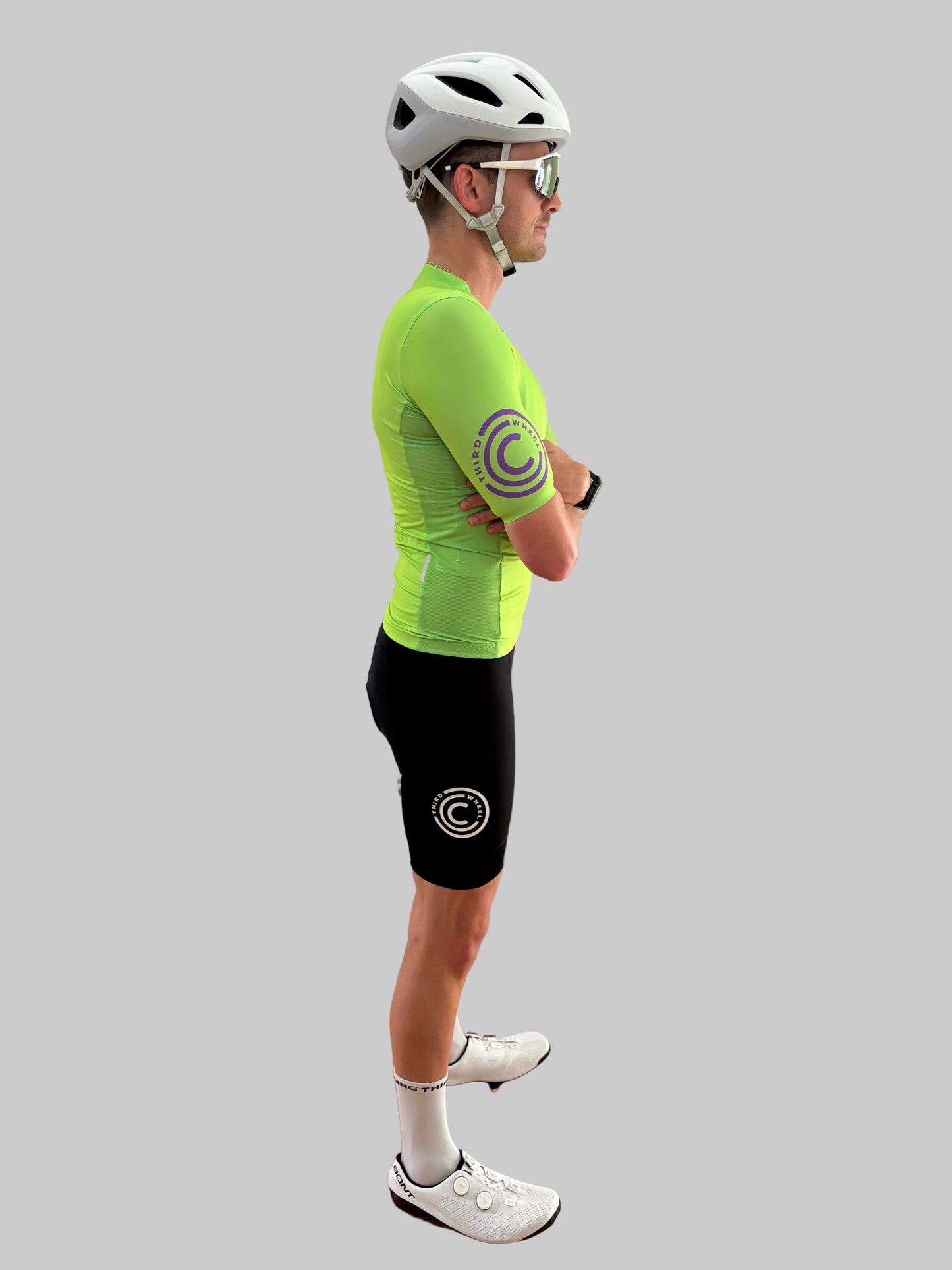 Person wearing a bright green cycling jersey and black shorts with a logo on a gray background