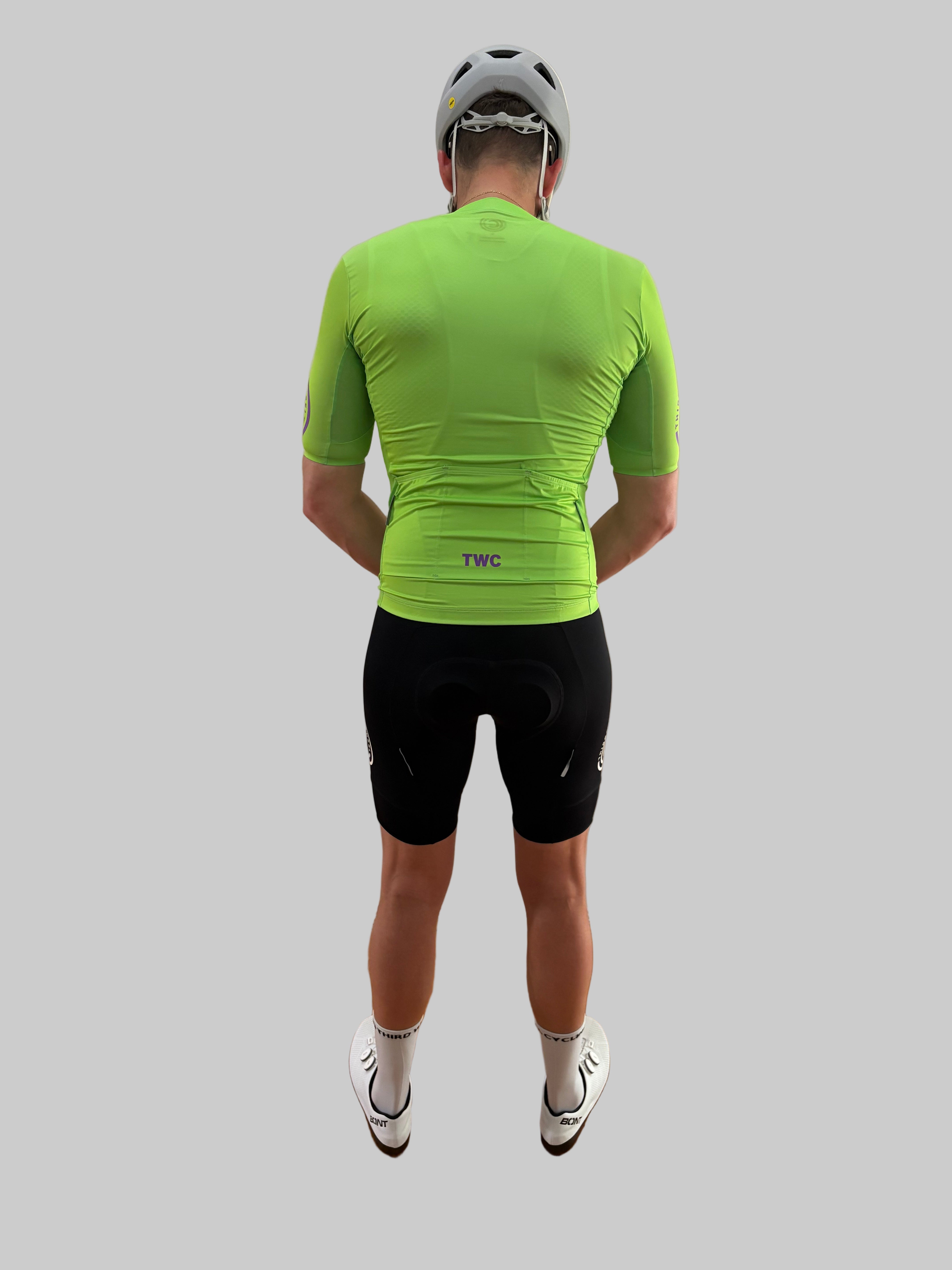 Person wearing a bright green cycling jersey and black shorts on a gray background