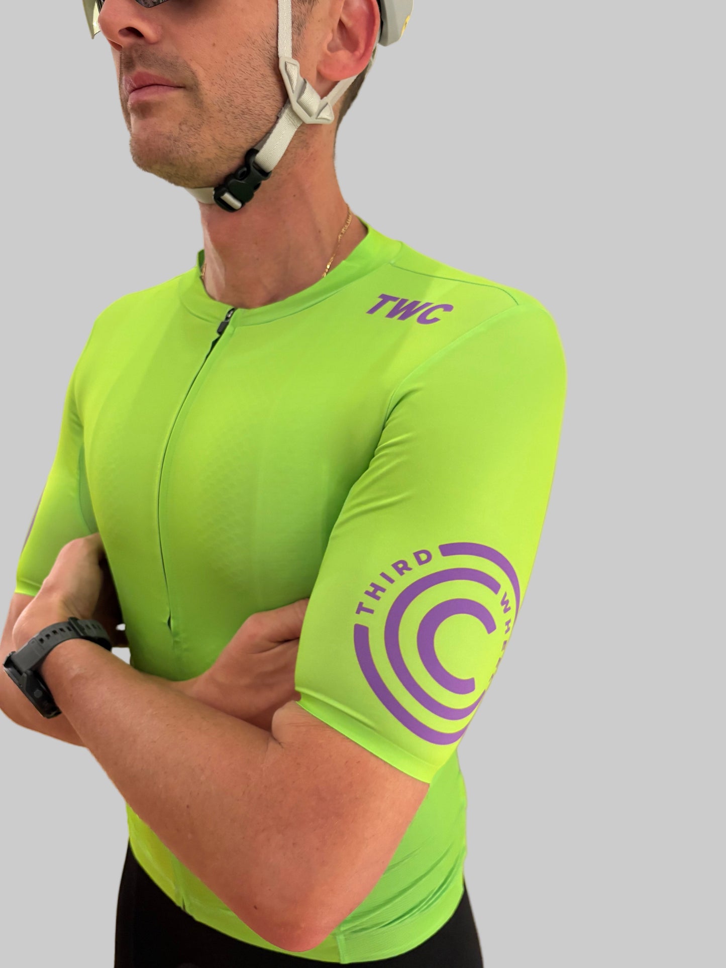 Person wearing a bright green cycling jersey with 'TWC' branding on a gray background