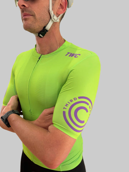 Person wearing a bright green cycling jersey with 'TWC' branding on a gray background