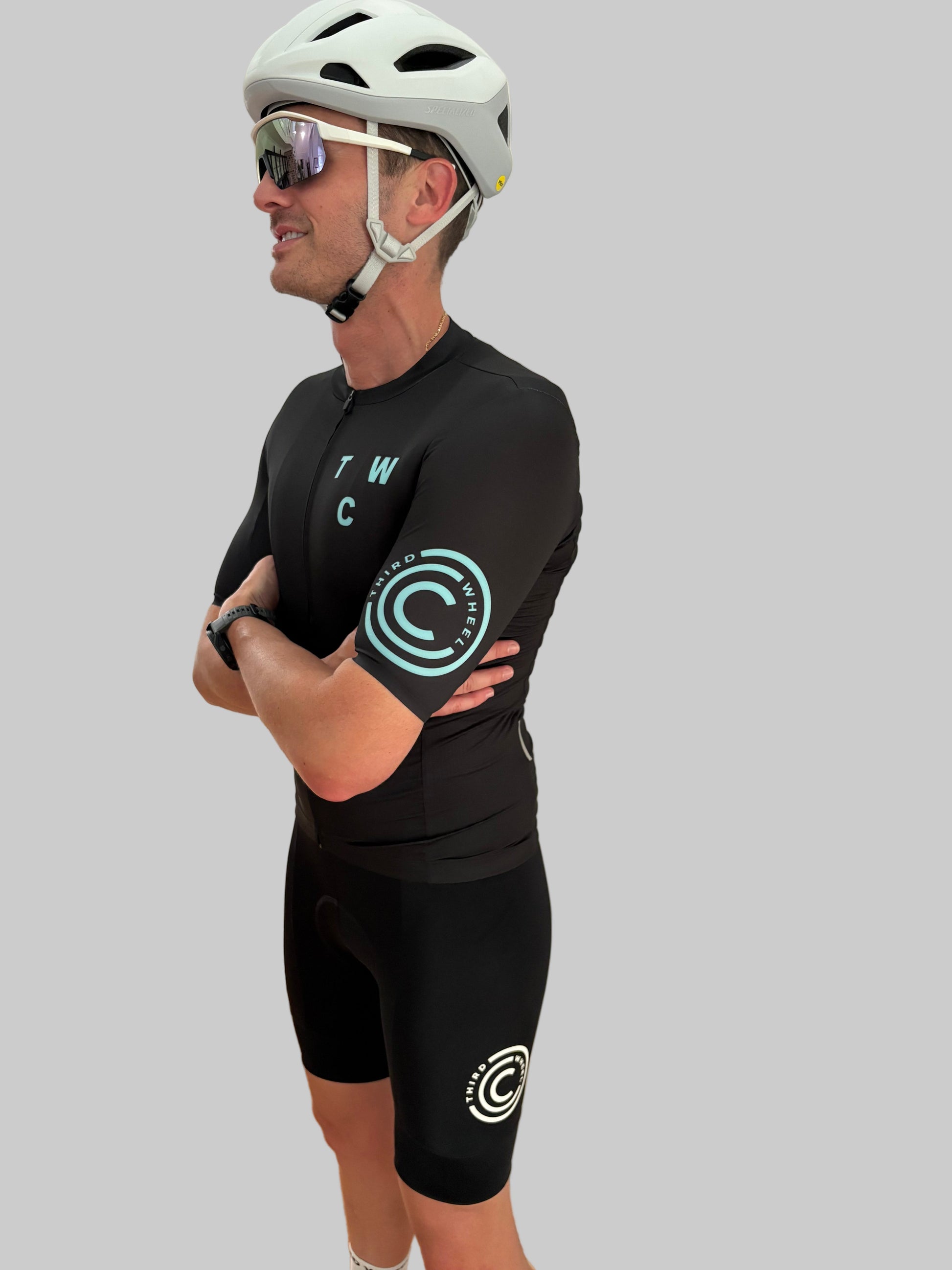 Person wearing a black cycling outfit with visible branding on a gray background