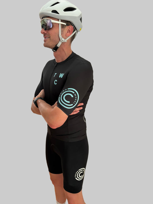 Person wearing a black cycling outfit with visible branding on a gray background